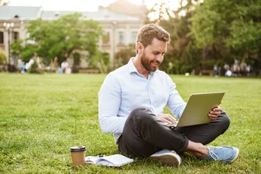 Mann auf Wiese mit einem Laptop